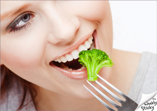 A woman eating broccoli